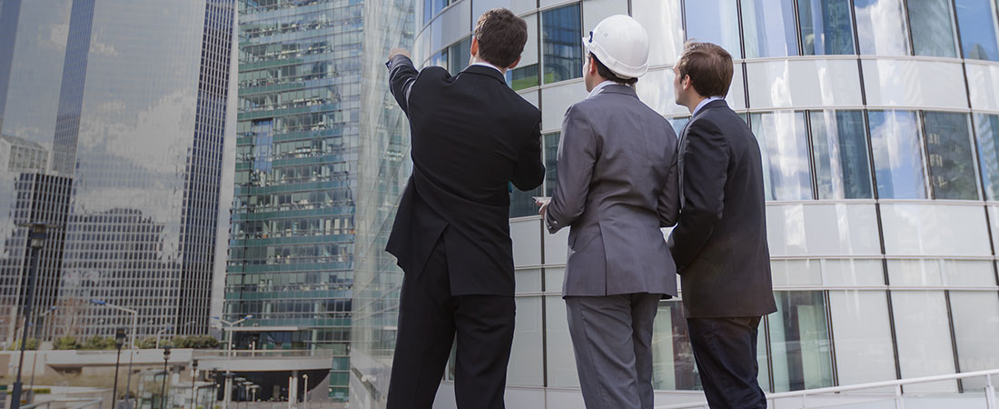 three men in suits looking at buildings